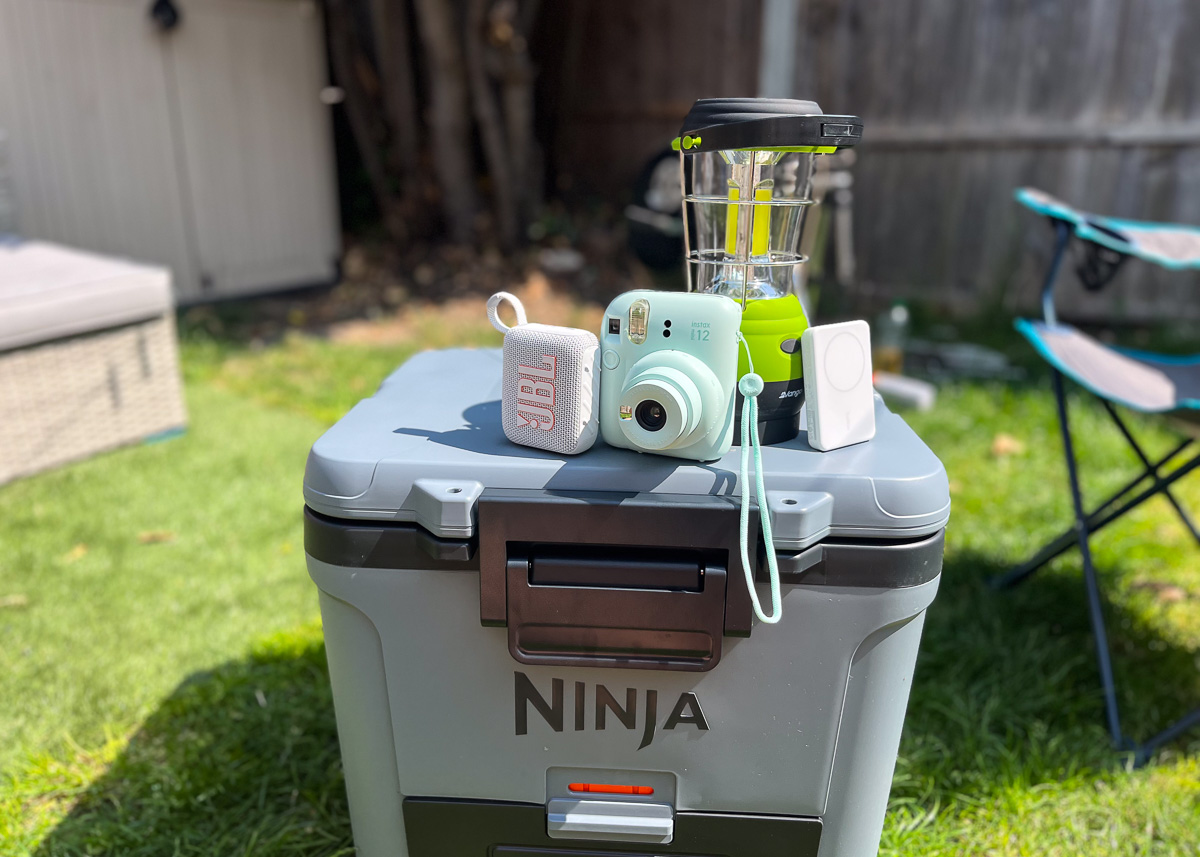 JBL speaker, portable charger, Instax camera and camping lamp on top of a Ninja cooler