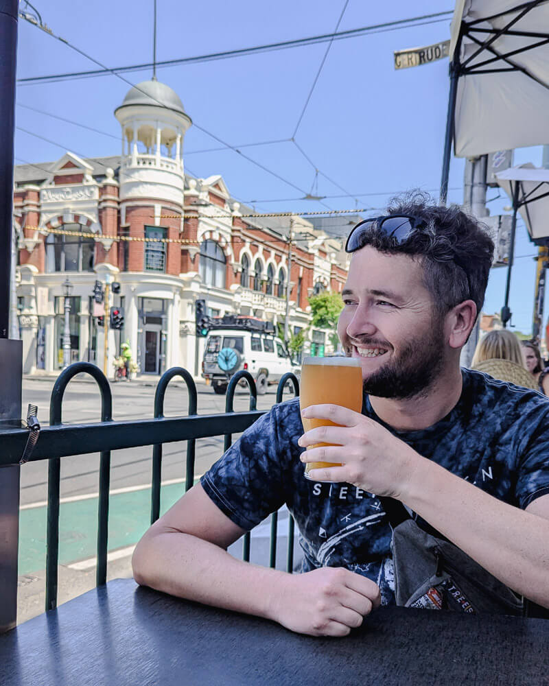 Man drinking a beer on a roadside bar table in Melbourne