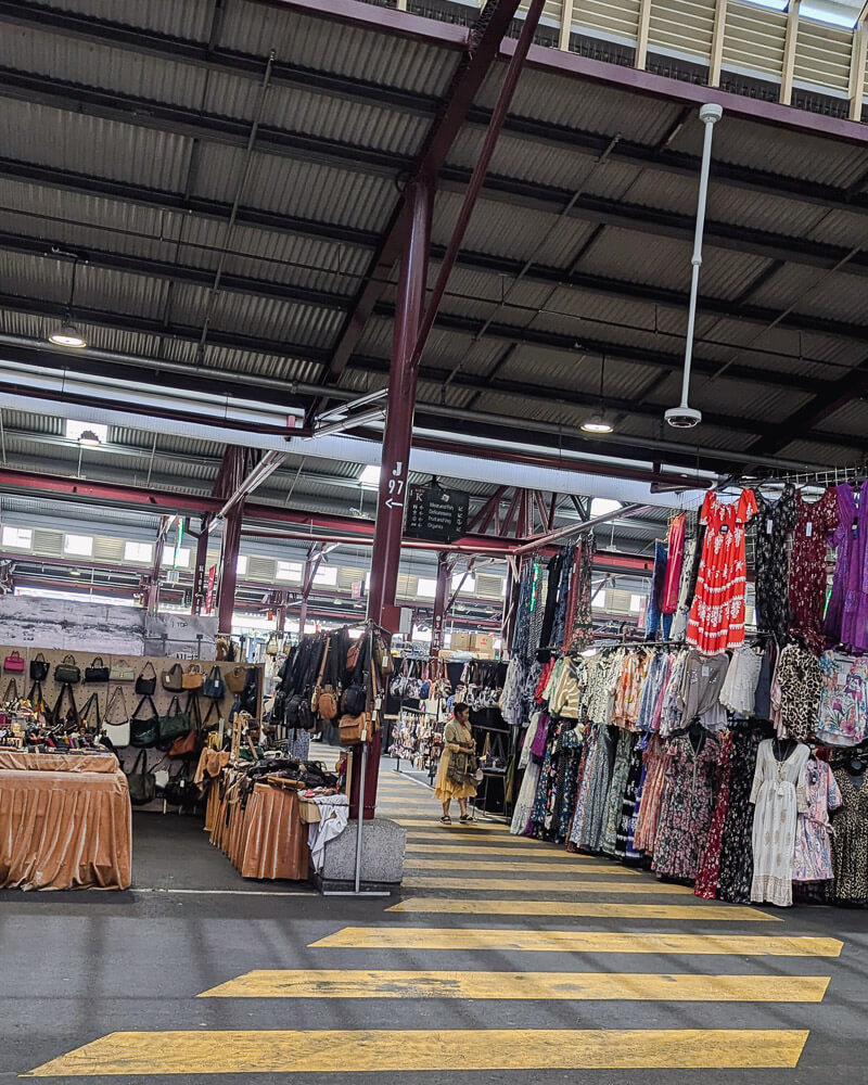 Stalls with two stacked rails of colourful clothing items at Queen Victoria Market