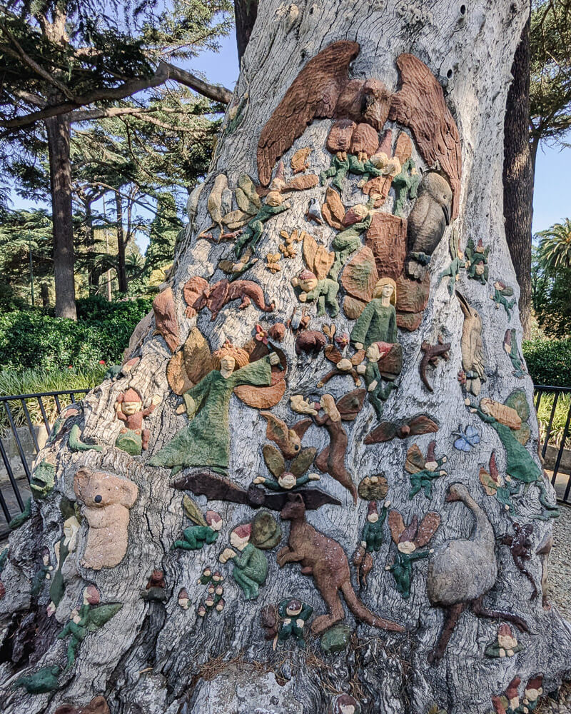 Carvings of mythical creatures and animals on a tree in Fitzroy Gardens