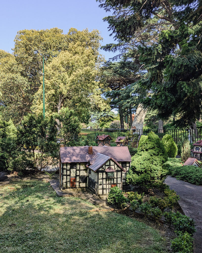 Model tudor house surrounded by grass and trees.